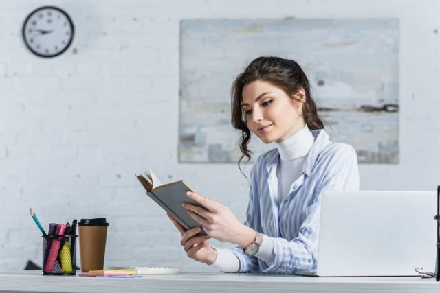 woman reading a book on how to become a proofreader