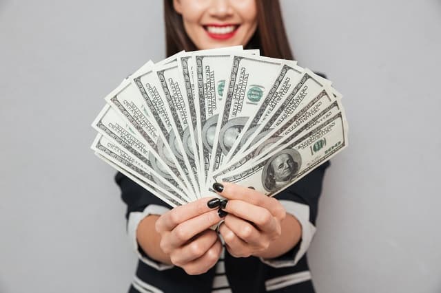 woman holding $5000 in cash
