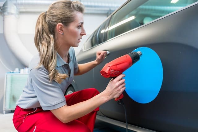 Woman with legitimate car wrap advertising company installing decal