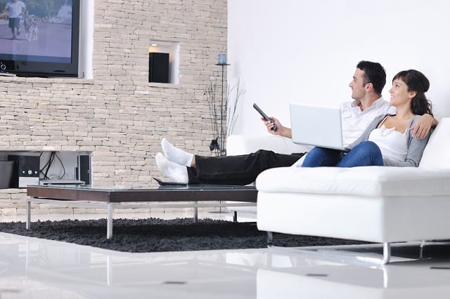 couple watching tv while getting paid to live in a house