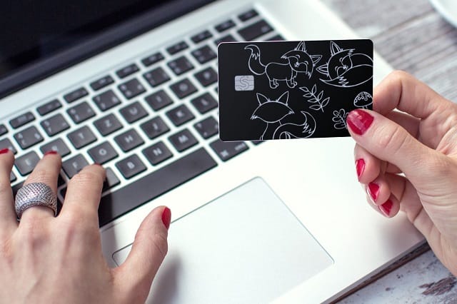 woman holding free gift card in front of laptop