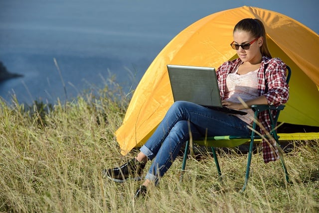 woman working on laptop and getting paid to camp