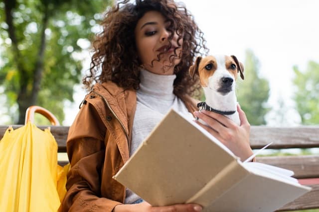 Woman reading next to a dog