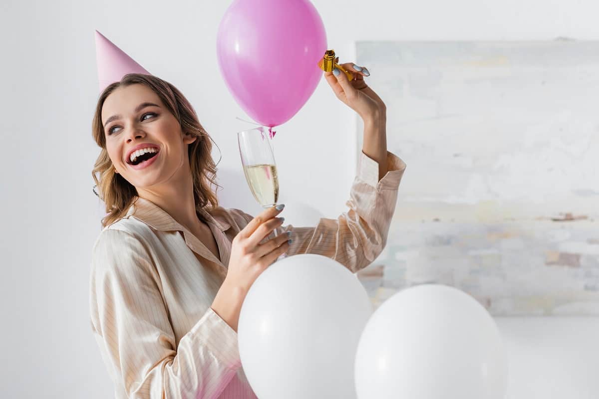 Woman holding ballon and wine glass to celebrate party she planned
