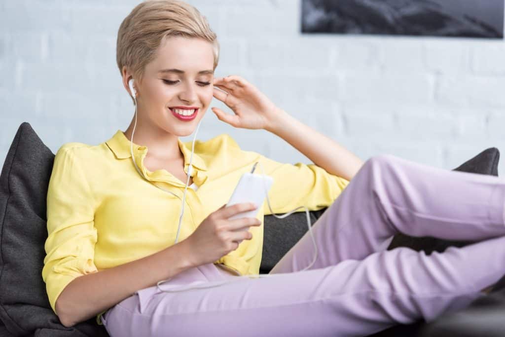 Young woman listening to earbuds while on a smartphone