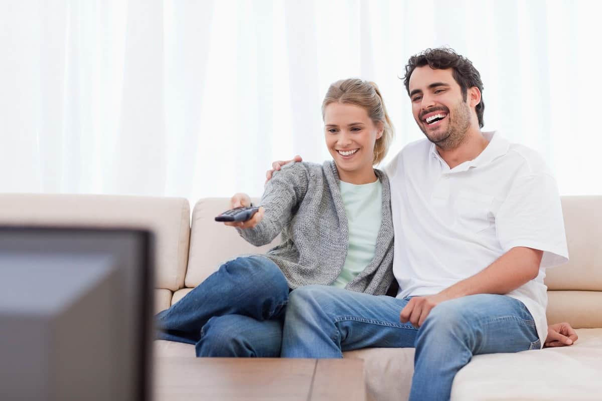 Couple sitting on couch watching The Office on TV