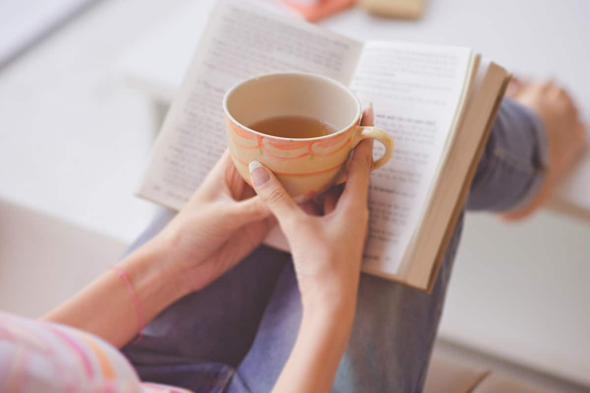 Woman holding tea and a free Christian book