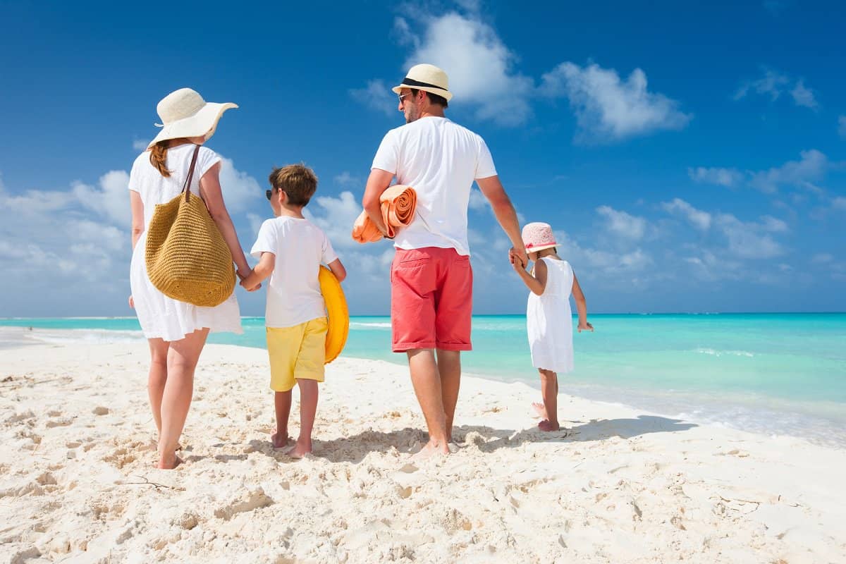 Family walking on a beach getting paid to go on vacation