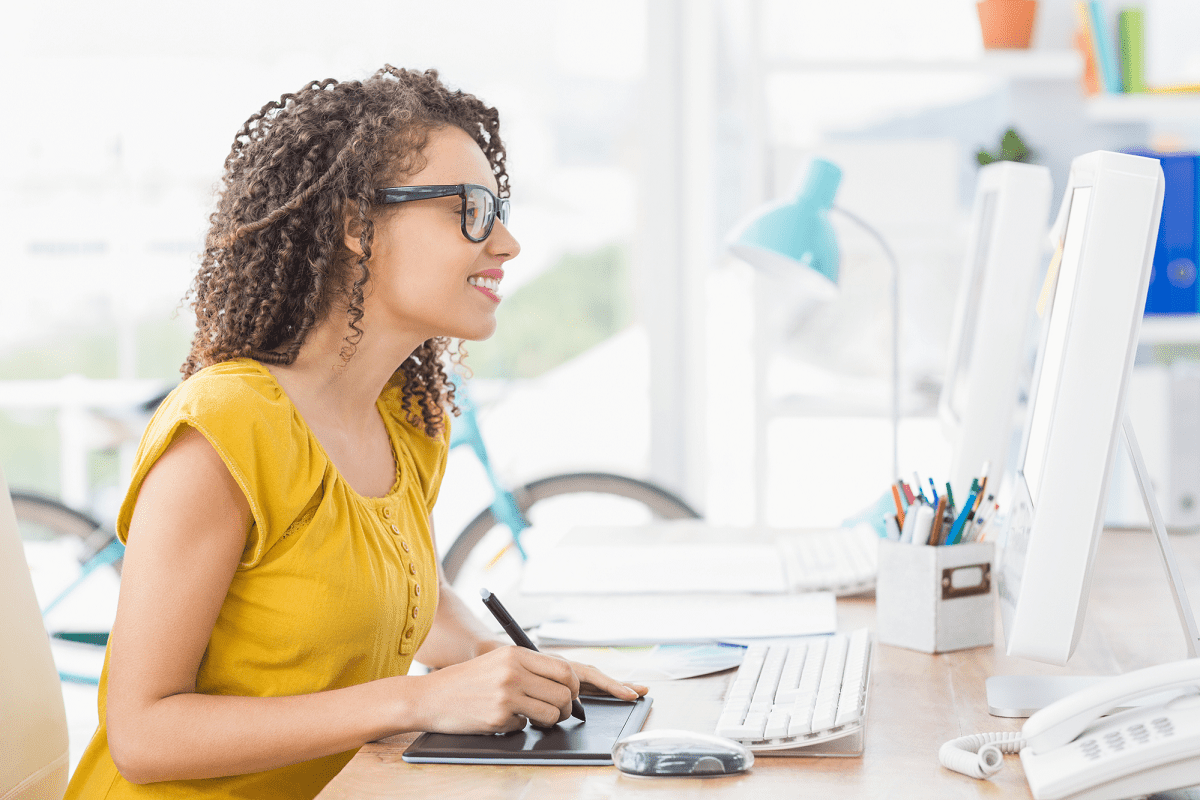 Woman smiling at computer screen while research photo editing courses