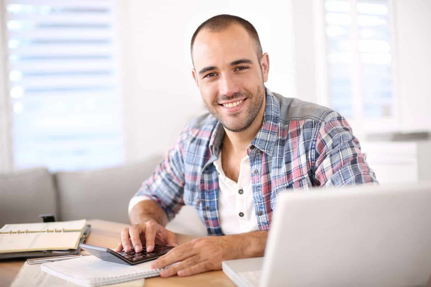 Man smiling working on a laptop
