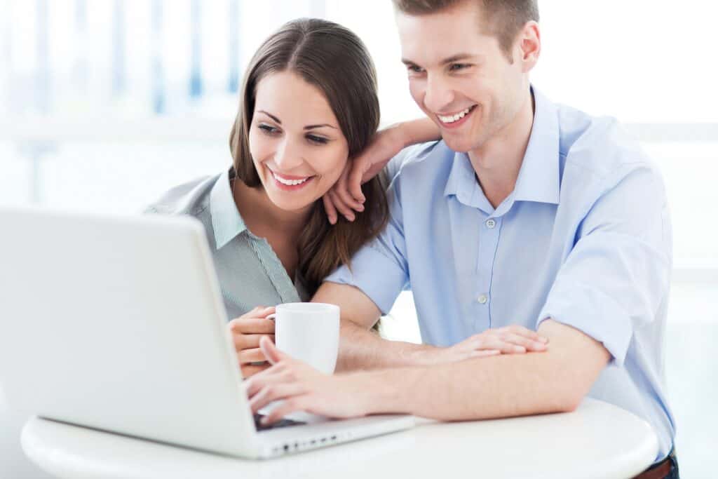 happy couple managing finances on a laptop