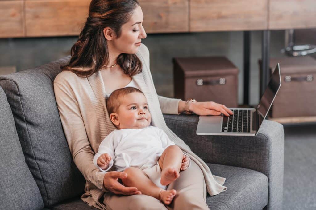 woman holding baby working on a laptop