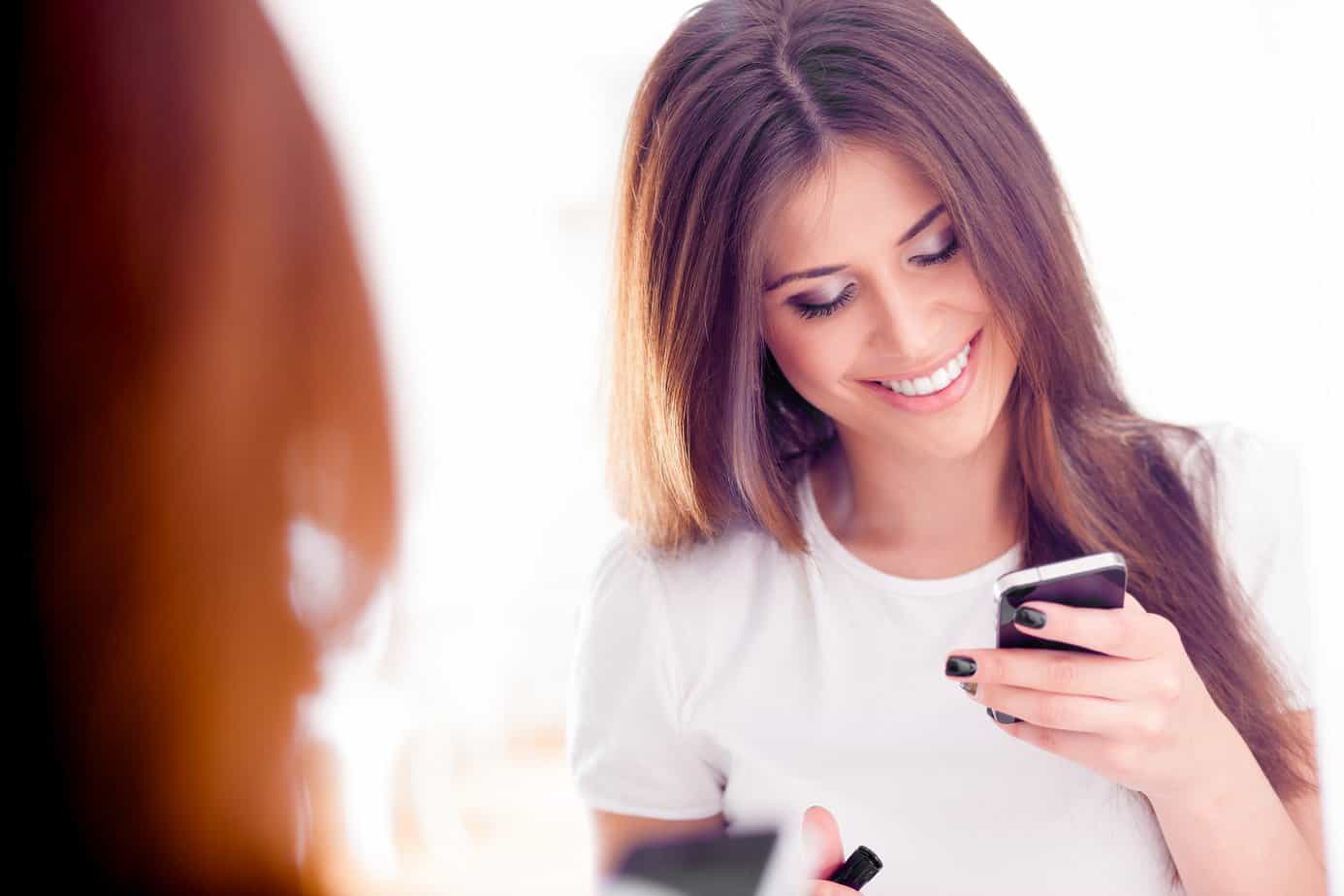 Woman smiling looking down at smartphone