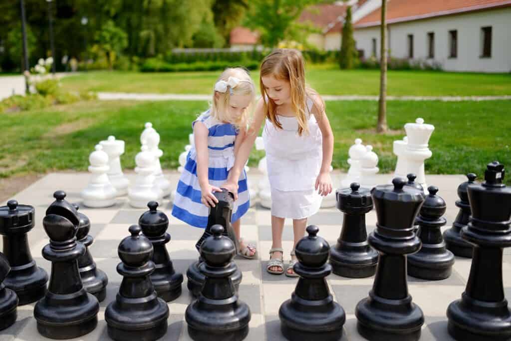 little girls playing on a giant chess board