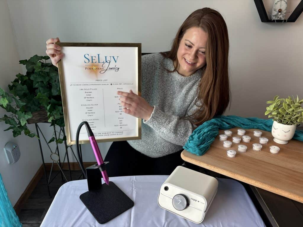 Trinity smiling pointing to SeLuv sign